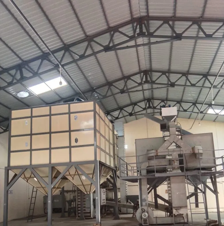 Wide view of the processing hall: a bank of steel holding silos on the left and the bagging line on the right
